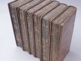 several old books stacked on top of each other on a white surface