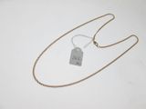 a gold chain with a tag attached to it on a white surface