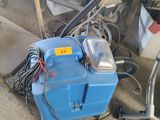 a blue machine that is sitting on the ground next to a pile of junk