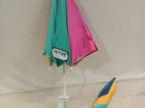 a colorful umbrella that is on the ground next to a sign