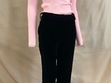 un pull à col roulé rose et un pantalon noir posés sur un socle de mannequin