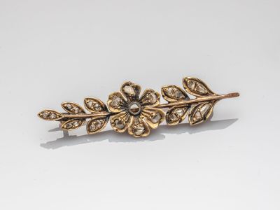 un gros plan sur une barrette dorée ornée d'une fleur