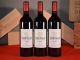 three bottles of red wine sitting on a table next to a wooden box
