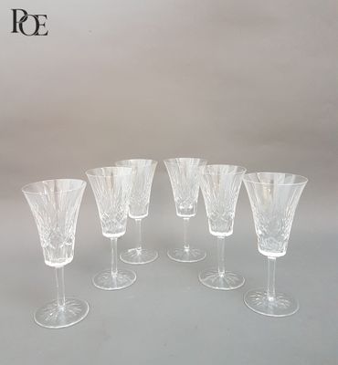 six verres à vin transparents sont alignés sur une table