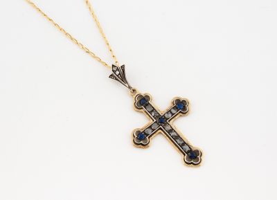un pendentif en forme de croix en or, orné de saphirs bleus, monté sur une chaîne en or