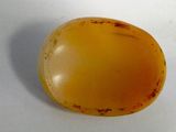 a close up of a yellow stone on a white surface