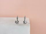 une paire de boucles d'oreilles à clous en diamant posée sur un bloc de marbre