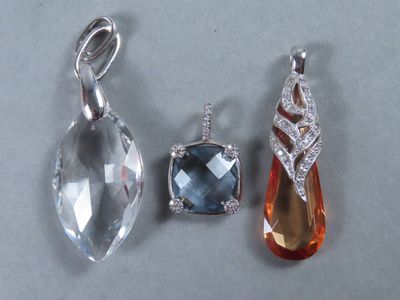 Trois pendentifs de formes et de couleurs différentes sont posés sur une table