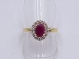 a close up of a gold ring with a ruby and diamond center