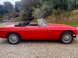 an image of a red convertible car parked in a gravel lot