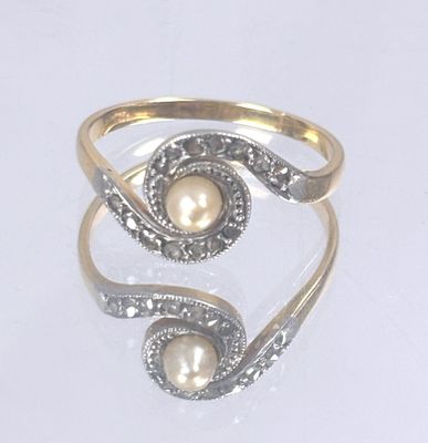 a ring with a pearl inside of it on a white surface