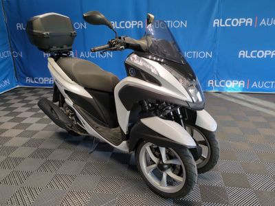 une photo d'un scooter blanc et noir garé devant un fond bleu