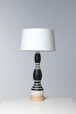 La lampe noire et blanche est posée sur une table blanche.
