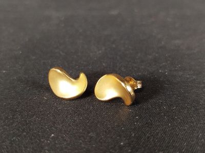 une paire de boucles d'oreilles en or posée sur une surface noire