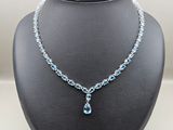 un collier orné d'une topaze bleue et d'une chaîne en argent, présenté sur un mannequin