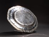 a silver plate sitting on a stand on a black surface