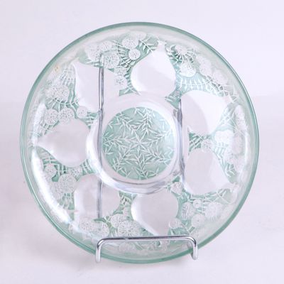 un saladier en verre posé sur un socle en métal, posé sur une surface blanche
