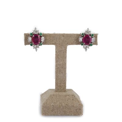 une paire de boucles d'oreilles en rubis et diamants, posées sur un présentoir