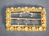 an image of a gold broochle with pearls on it