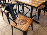 tables and chairs in a restaurant with a wooden table and black chairs