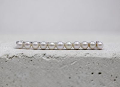 un gros plan d'une bague en perle blanche posée sur une surface en béton