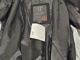 the back of a jacket with a tag on it sitting on a bed
