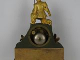 a gold statue of a man sitting on top of a clock