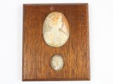 une plaque en bois sur laquelle figurent le portrait d'une femme et une pièce de monnaie