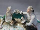 a figurine of a man and a woman sitting on a bed