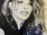 an autographed photograph of a woman with long hair and a black top
