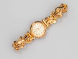 gros plan d'une montre-bracelet en or sur une surface blanche