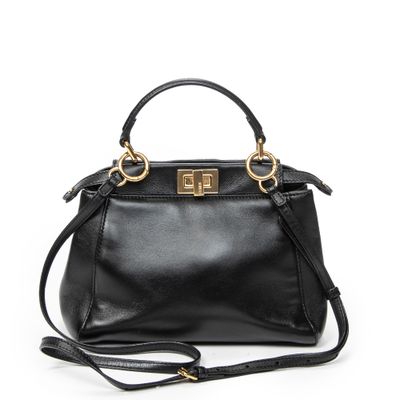 un sac à main en cuir noir avec des finitions dorées sur fond blanc