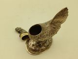 a silver vase with a bird on it on a table