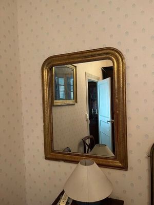 un miroir accroché au mur au-dessus d'une lampe dans une pièce