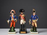 trois figurines représentant des hommes en uniforme militaire posées sur une surface blanche