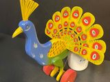 a toy peacock that is sitting on top of a toy car
