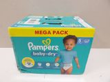 Des culottes-couches « Pampers Baby Dry » dans une boîte posée sur une table