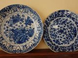 une paire d'assiettes bleues et blanches ornées de motifs floraux, posées sur une étagère