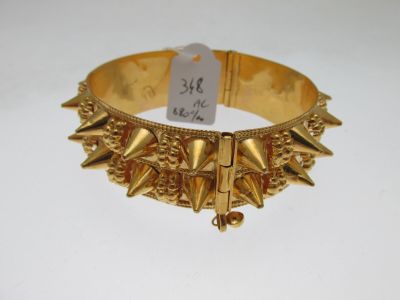 un gros plan sur un bracelet en or orné de pointes