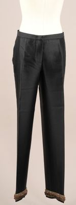 Le pantalon est noir et comporte une bande marron.