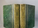 une paire de livres verts à la couverture dorée posés sur une surface blanche