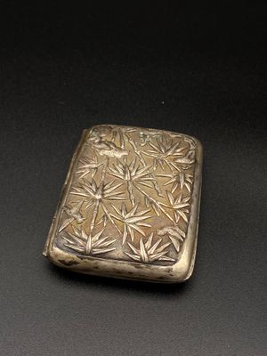 un étui à cigarettes ancien en argent posé sur une surface noire