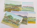 four cards with watercolor paintings of a landscape on a white surface