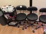 Plusieurs tabourets et chaises noirs sont alignés contre un mur
