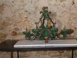 a green chandelier on a table in front of a stone wall