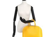 a mannequin holding a yellow handbag on top of a mannequin dummy