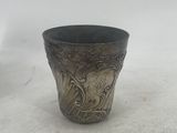 a silver cup that is sitting on a white surface