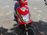 a red scooter parked on the side of the road