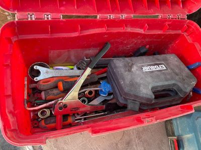 une boîte rouge contenant des outils, posée par terre