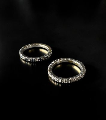 two gold rings with diamonds on a black background